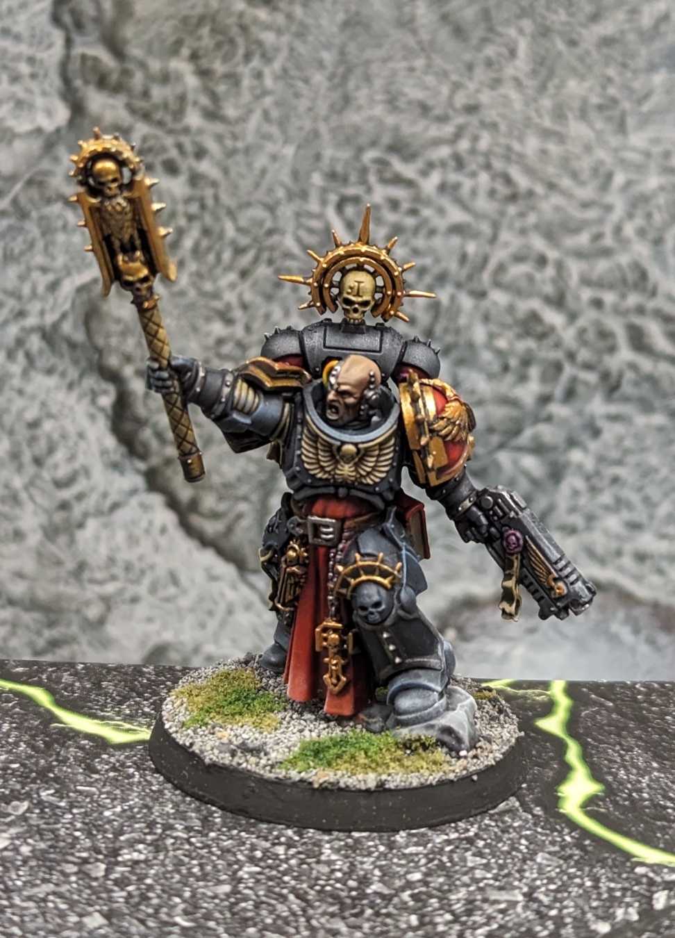 Warhammer 40k Space Marine Chaplain with black armor, red cloth, lots of gold trim.